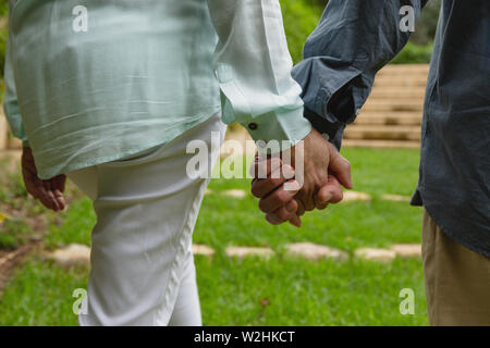 Active senior couple standing together hand in hand at garden Stock Photo