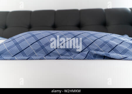 Image of blue textured pillow in black bed with white blanket Stock Photo