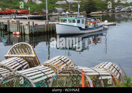 Wooden lobster traps and a fishing boat in Peggy's Cove, Nova Scotia Stock Photo