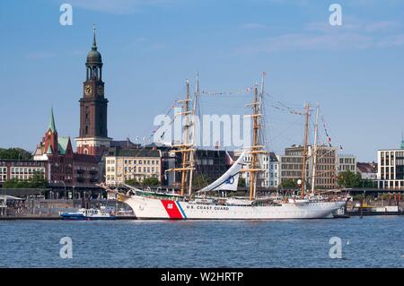 The 'Eagle' is the sail training ship of the United States Coast Guard located in the Port of Hamburg on the St. Pauli-Landungsbrucken in front of the Rickmer Rickmers, in the background of the Michel. Originally a sail training ship of the German Navy with the name 'Horst Wesel', the three-master went after the end of the war in 1946 as a reparation in the US. Traditionally, all Coast Guard ships are referred to as cutters. Therefore the Prafix USCGC = United States Coast Guard Cutter. As the German sailing training ship 'Gorch Fock', she is one of six sailing ships of the 'Gorch Fock' class. Stock Photo