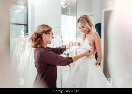 Tailor taking measures of a young woman. Stock Photo