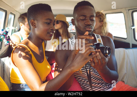 Friends reviewing photos on digital camera in camper van at beach Stock Photo