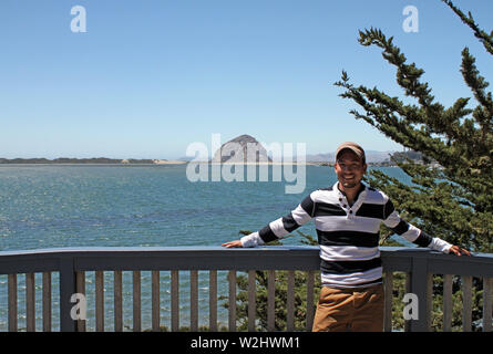 Young man with baseball cap standing next to the coast in California Stock Photo