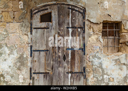 Texture of an old wooden wooden door with unusual metal handles on the island of Malta Stock Photo