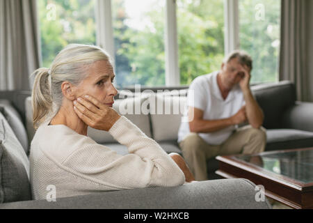 Active senior woman with hand on face sitting on sofa in a comfortable home Stock Photo