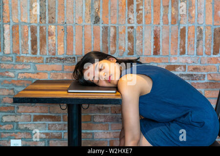 Restless woman falling asleep on laptop at rustic brick wall Stock Photo