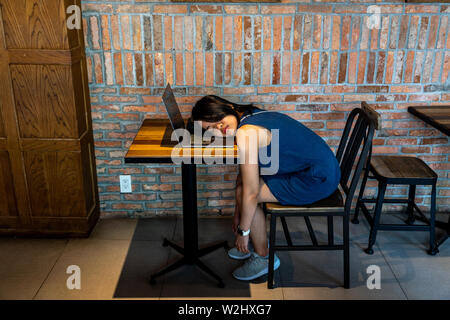 Young exhausted woman fall asleep on her laptop keyboard Stock Photo
