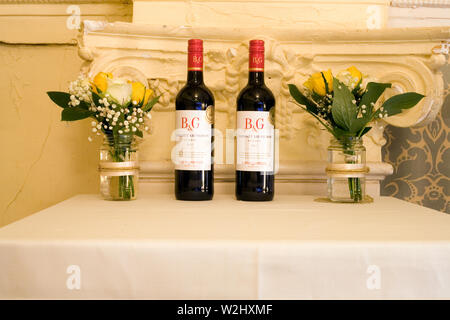 Display table with two jars of flowers and two bottles of Barton & Guestier cabernet sauvignon red wine at a couple's 50th wedding anniversary party Stock Photo