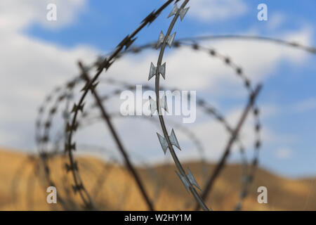 Barbed wire drawn in circles against a background of mountains Stock Photo