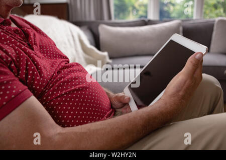 Active senior man using digital tablet on sofa in a comfortable home Stock Photo