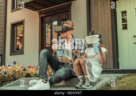 Modern blonde father sitting on the porch with his daughter
