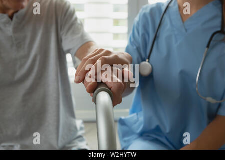 Female doctor consoling active senior man at home Stock Photo