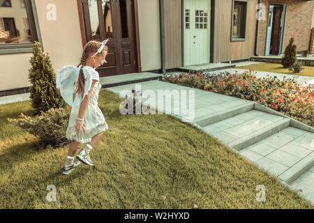 Active pretty girl walking on the green lawn in light costume Stock Photo