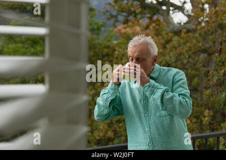 Active senior man drinking coffee on the balcony Stock Photo