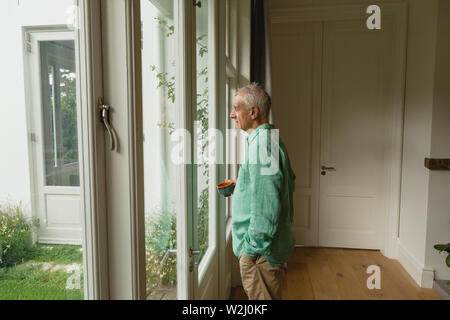 Active senior man standing with coffee cup at home Stock Photo