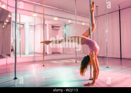 Dancer standing on her hands near the pole. Stock Photo