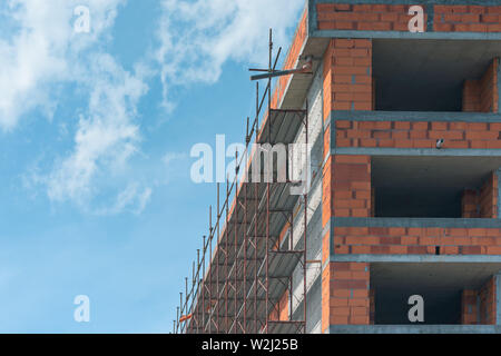 Scaffolding on empty construction site with unfinished incomplete building and blank sky as copy space Stock Photo