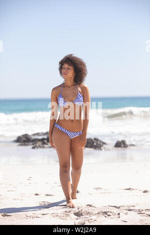 Woman in bikini walking on the beach Stock Photo