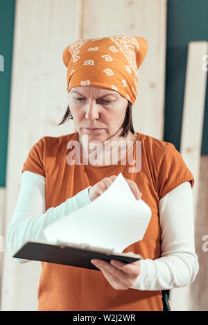 Female carpenter reading DIY project notes in small business woodwork workshop Stock Photo