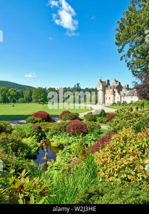 BALLINDALLOCH CASTLE AND GARDENS BANFFSHIRE SCOTLAND THE POND AND MEN MOWING THE LAWNS Stock Photo