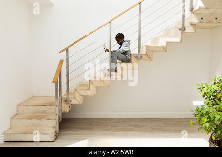 Boy using digital tablet on staircase at home Stock Photo