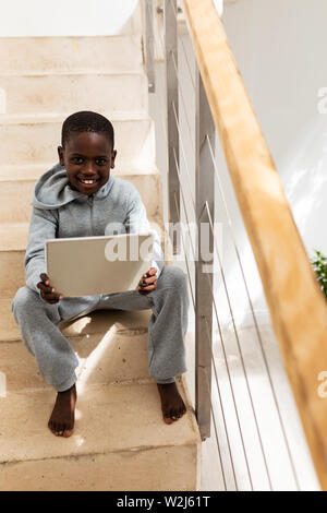 Boy using digital tablet on staircase at home Stock Photo