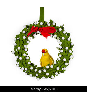 Red crowned yellow Kakariki bird, sitting side ways in a mistletoe Christmas wreath. Isolated on white background. Stock Photo