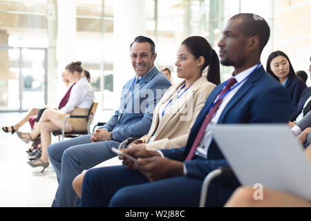 Group of diverse executives sat in conference room, smiling to camera Stock Photo