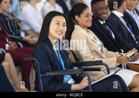 Young Asian businesswoman sat on wheelchair listening to speech in conference room Stock Photo