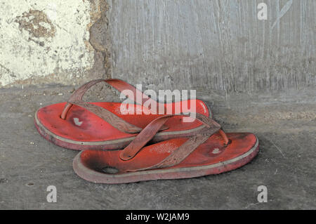 yogyakarta, di yogyakarta/indonesia: a pair of worn out plastic sandals on the ground  in front of a residential house in the yogyakarta vicinity Stock Photo
