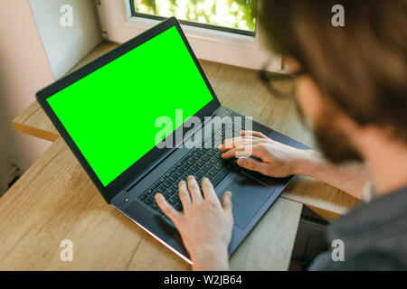 Bearded man relaxing on sofa at home using green screen laptop Stock Photo