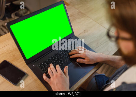 Over the shoulder shot of a man typing on a computer laptop with a key green screen Stock Photo