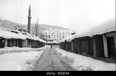 28th March 1993 During the Siege of Sarajevo: the view south of closed-up shops and stalls in the square in Bascarsija. Bascarsija mosque in the background. Stock Photo