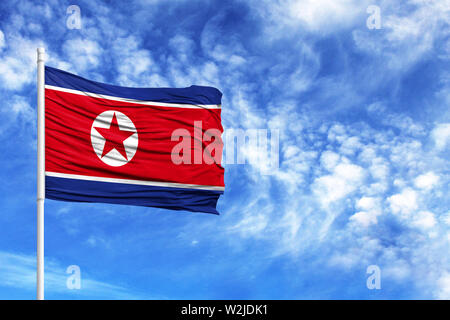 National flag of North Korea on a flagpole in front of blue sky Stock Photo