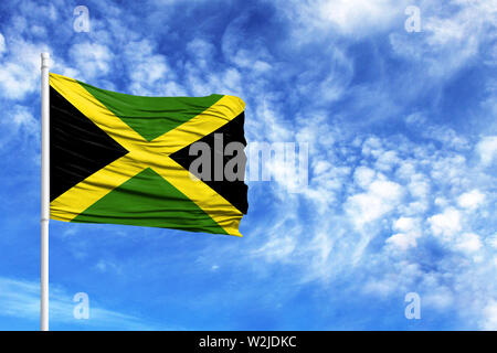 National flag of Jamaica on a flagpole in front of blue sky Stock Photo