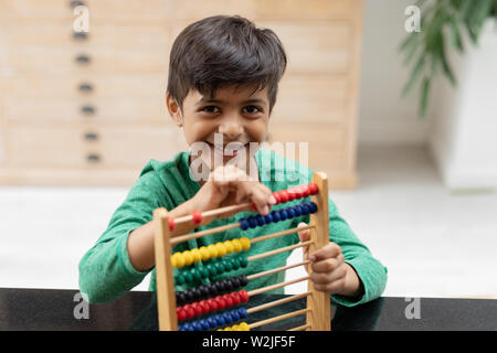 Boy playing with abacus on a table at home Stock Photo