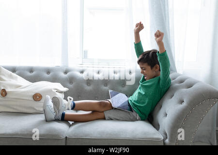 Boy playing games on digital tablet in living room at home Stock Photo