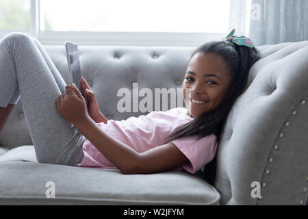 Girl using digital tablet on a sofa in living room Stock Photo