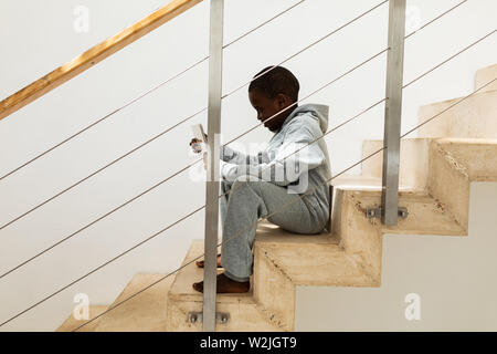 Boy using digital tablet on staircase at home Stock Photo