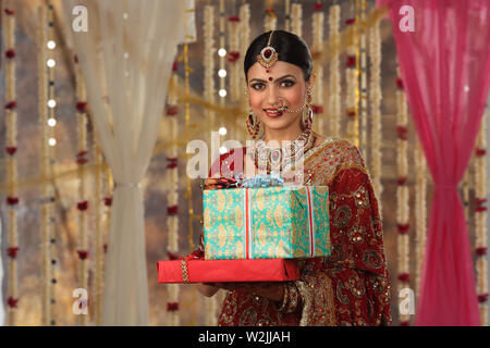 Portrait of an Indian bride holding gift boxes and smiling Stock Photo