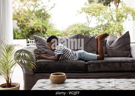 Boy using digital tablet on a sofa in living room Stock Photo