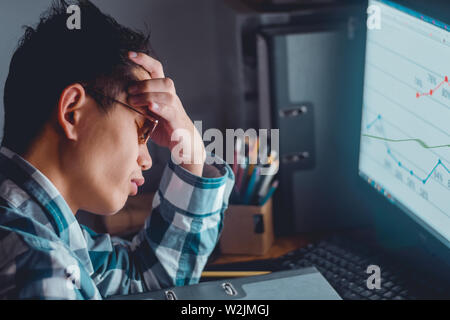 Fatigue man having a headache at office in while watching computer totally exhausted working late at night. Stock Photo