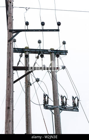 A mess of power cables and insulators on wooden power poles. Stock Photo