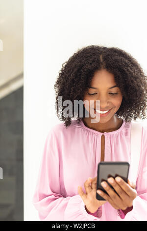 Young pretty African-american employee looking her phone Stock Photo