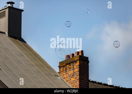 Big soap bubbles in air with  chimney  in the background in Ghent, Belgium Stock Photo