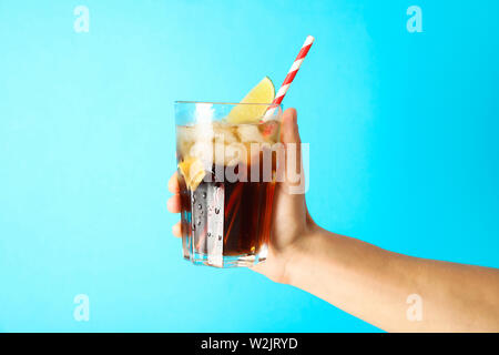 Female hand holding a glass with ice cola, tubule and lime slice Stock Photo