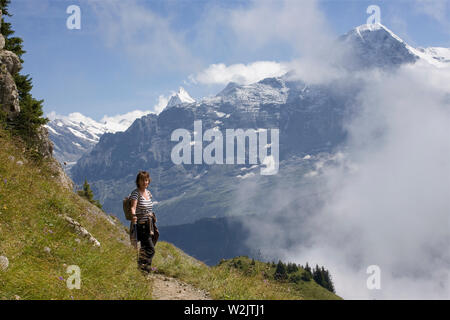 Female hiker on the Panoramaweg on Schynige Platte, Bernese Oberland, Switzerland, with the Eiger looming across the Lütschental Valley MODEL RELEASED Stock Photo