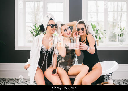 Picture showing group of happy friends in spa. girls with towels on heads having fun and taking selfie at home. Friendship, cosmetic, slumber party co Stock Photo