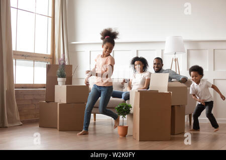 Active african kids running around boxes laughing on moving day Stock Photo