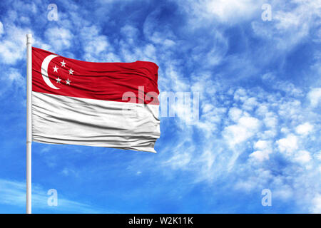 National flag of Singapore on a flagpole in front of blue sky Stock Photo